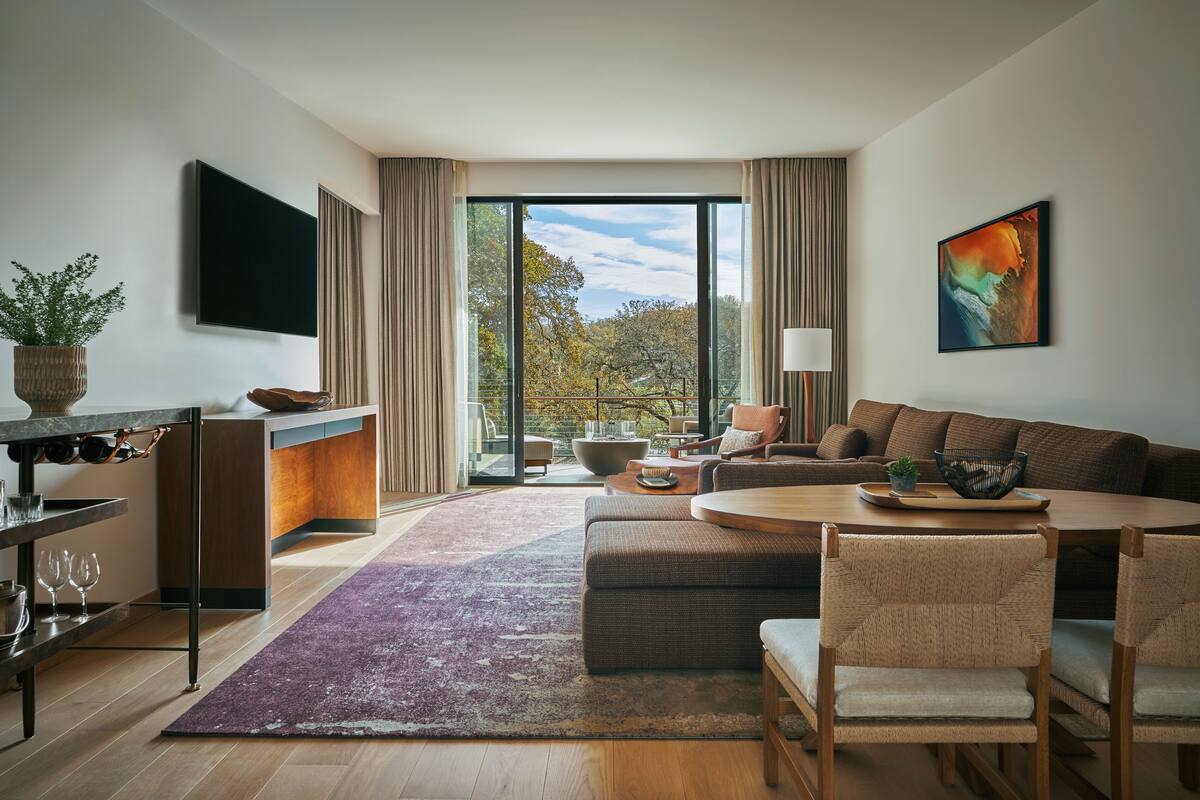 A modern living room with a sofa, dining table, and a TV mounted on the wall.