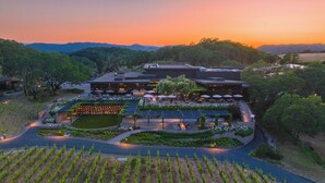 A vineyard with rows of grapevines, a modern building with a patio area, and a sunset in the background. - Montage Healdsburg (Healdsburg)