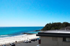 Vista sulla spiaggia con un parcheggio e un edificio a tetto piatto.