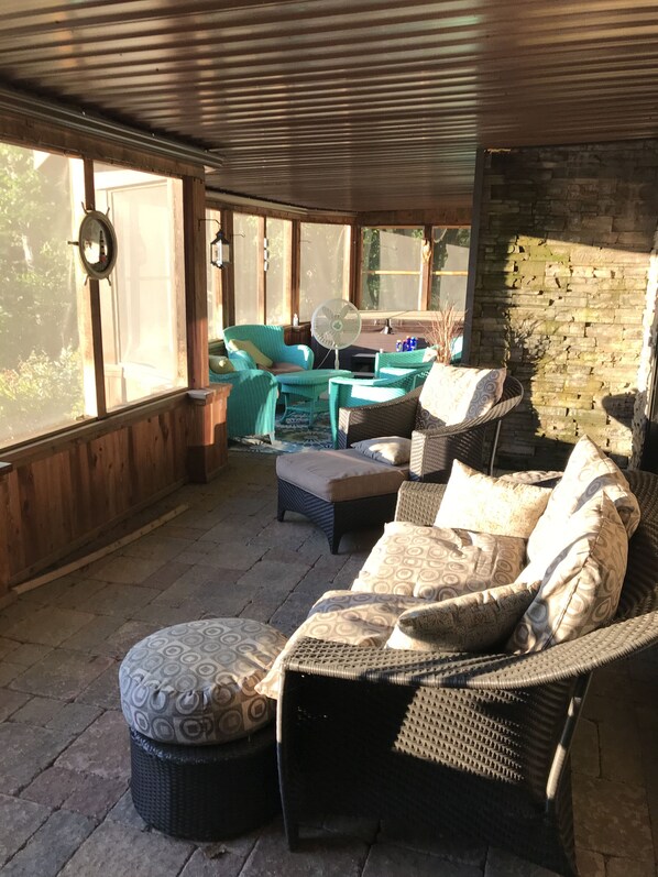 Relax in this charming outdoor seating area with a sofa set and matching ottoman, surrounded by exposed brick walls and large windows.