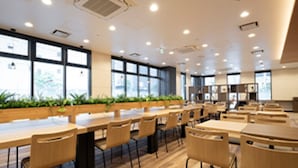 A modern dining area with wooden tables and chairs, large windows, and indoor plants. - R&B Hotel Nagoya-Ekimae (Nagoya)