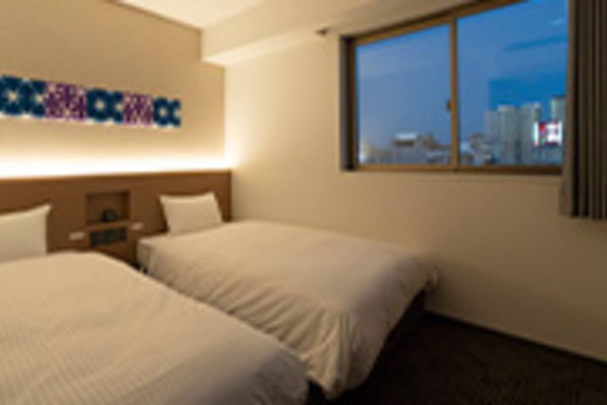 A hotel room with two beds, a city view through the window, and a sign on the wall.