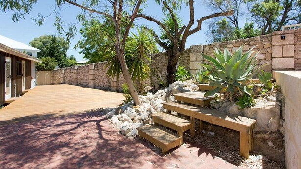 A wooden deck with stone walls and a stone wall with a wooden bench.