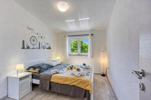 Et soveværelse med seng, sengeborde, et vindue og bykunst på væggen.
