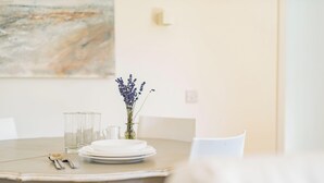 Een eettafel met borden, glazen en bestek, een vaas met bloemen en een stoel.