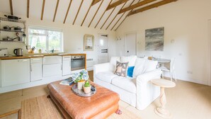 Een moderne keuken met witte kasten, een houten plafond en een eethoek met een witte tafel en stoelen.