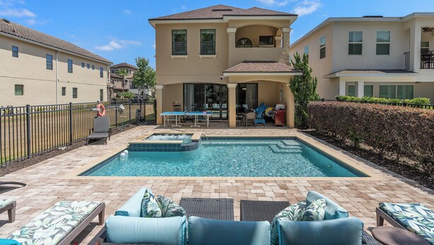 A two-story house with a swimming pool, outdoor seating, and a covered patio area. - 5-bedroom ALL SUITES PET FRIENDLY Luxury home Minutes to DISNEY & THEME PARKS (Reunion)