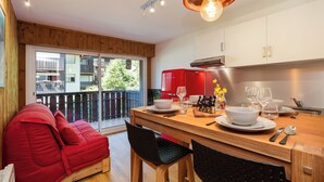 Une cuisine moderne avec un coin repas, un plancher en bois et un canapé rouge.