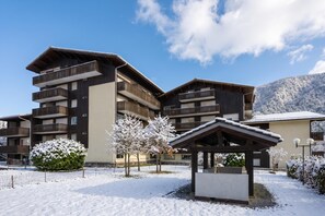 Ett hotell med flera våningar, balkonger, ett snötäckt område runt omkring och en bergskedja i bakgrunden.