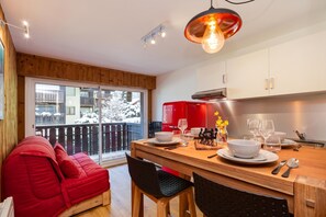 Une cuisine moderne avec un coin repas, un plancher en bois et une vue sur un paysage enneigé grâce à de grandes fenêtres.