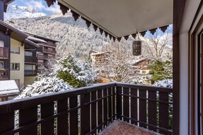 Un balcon offrant une vue sur des arbres et des montagnes enneigés.