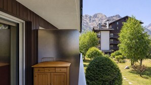 Un balcon doté d’une armoire en bois, d’une porte vitrée et offrant une vue sur un paysage montagneux.