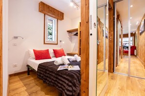 Une chambre à coucher avec un lit, une fenêtre, un miroir et un plancher en bois.