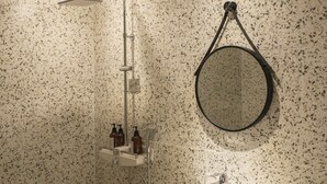 Un baño con lavamanos independiente, ducha y espejo redondo en la pared.
