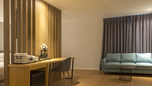 Un espacio habitable compacto con un separador de madera, una pequeña kitchenette, un comedor con una silla, un sofá y una mesa redonda de centro.