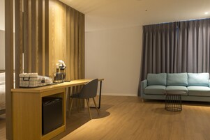 Un espacio habitable compacto con un separador de madera, una pequeña kitchenette, un comedor con una silla, un sofá y una mesa redonda de centro.