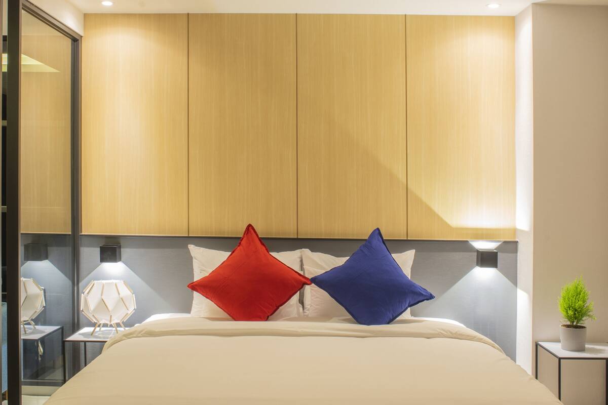 A modern bedroom with a large bed, wooden headboard, and bedside tables with lamps.