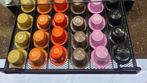 Una exhibición de recipientes coloridos en forma de cúpula, organizados en filas sobre un estante metálico.
