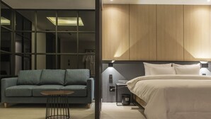 Una habitación de hotel moderna con cama, sofá, una mesita y un armario.