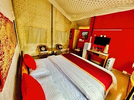 A hotel room with a bed, two chairs, a desk, a television, and a mirror.