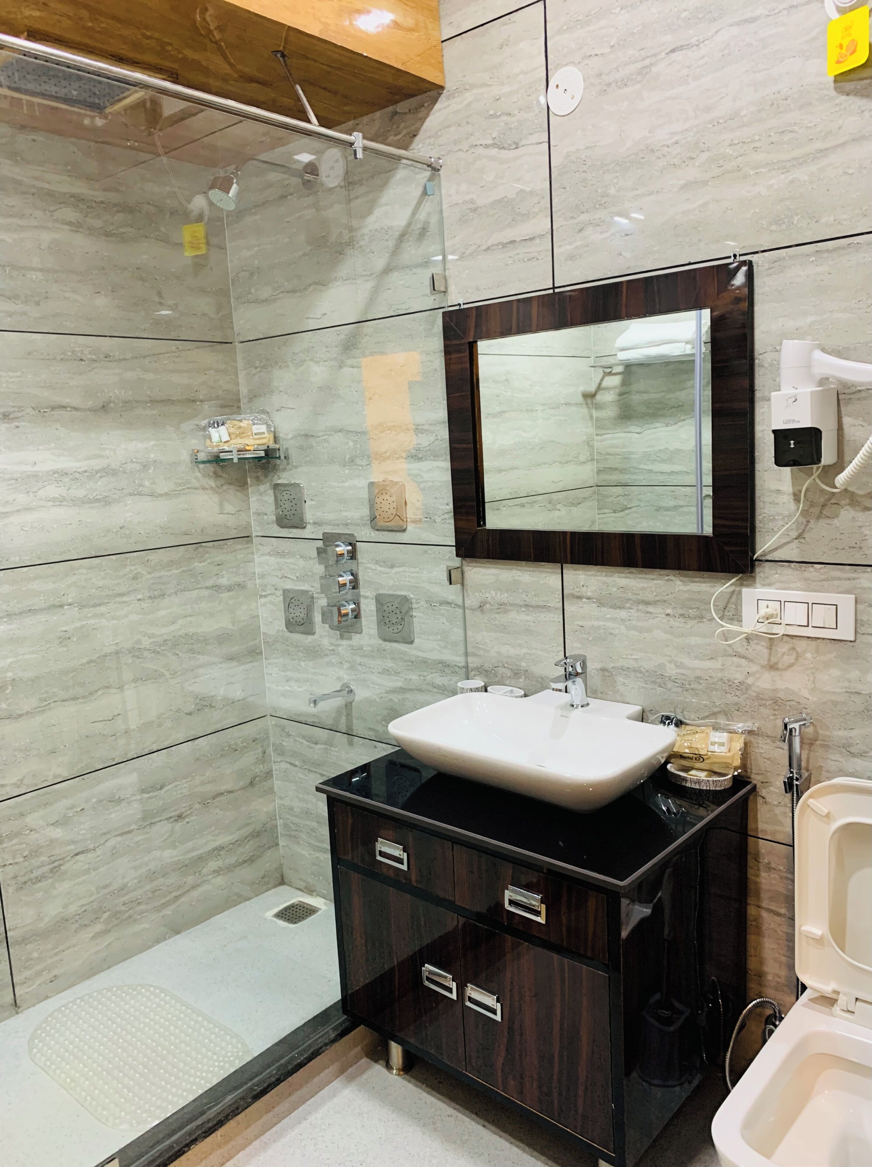 A modern bathroom with a glass shower enclosure, a vanity with a sink, and a mirror above the sink.