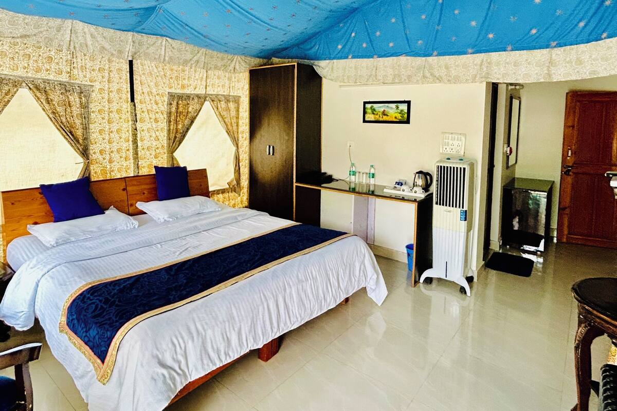 Une chambre à coucher comprenant un grand lit, une armoire, un bureau avec une chaise, un radiateur et une porte donnant sur une autre pièce.