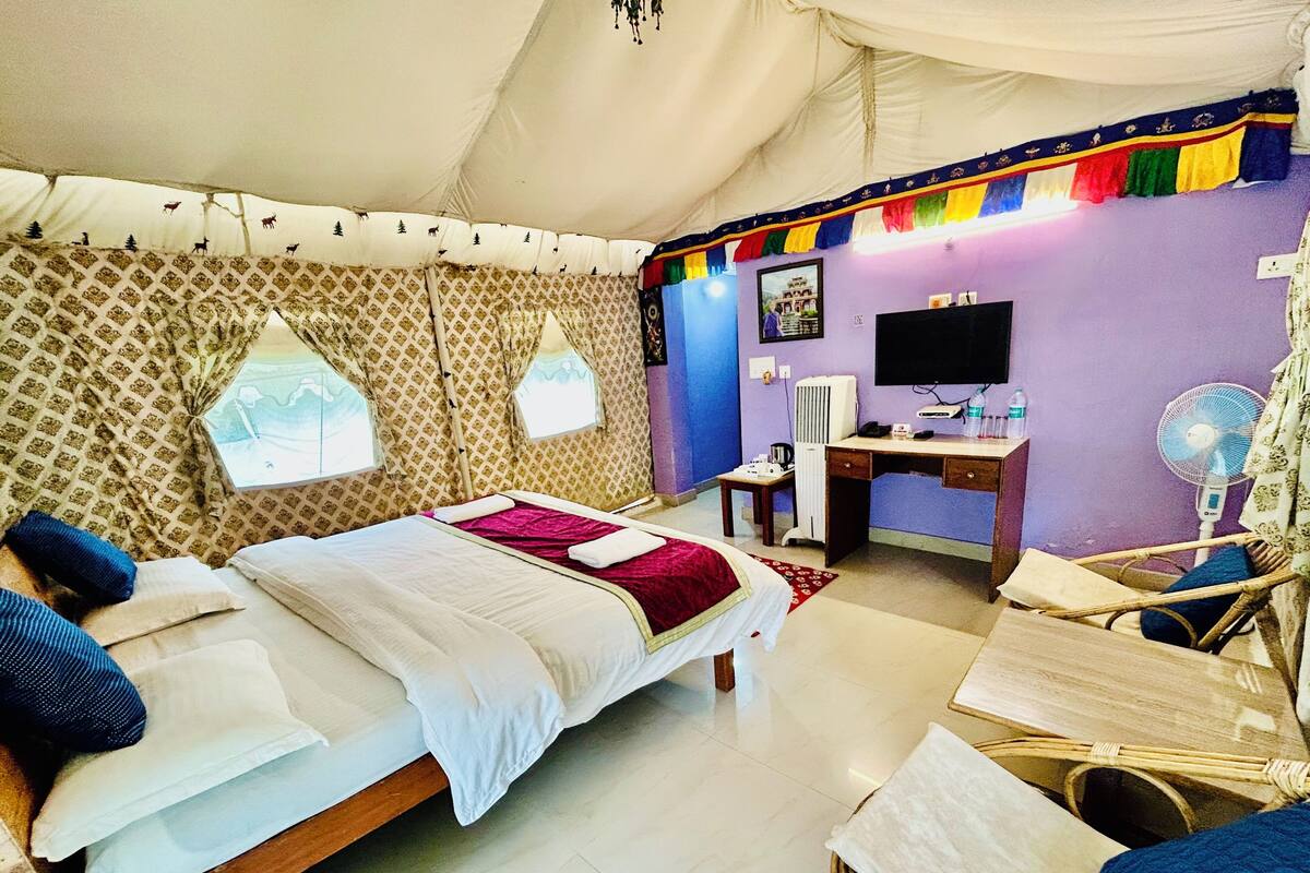 Une pièce aménagée avec une tente, comprenant un lit, un bureau, une chaise et un téléviseur.