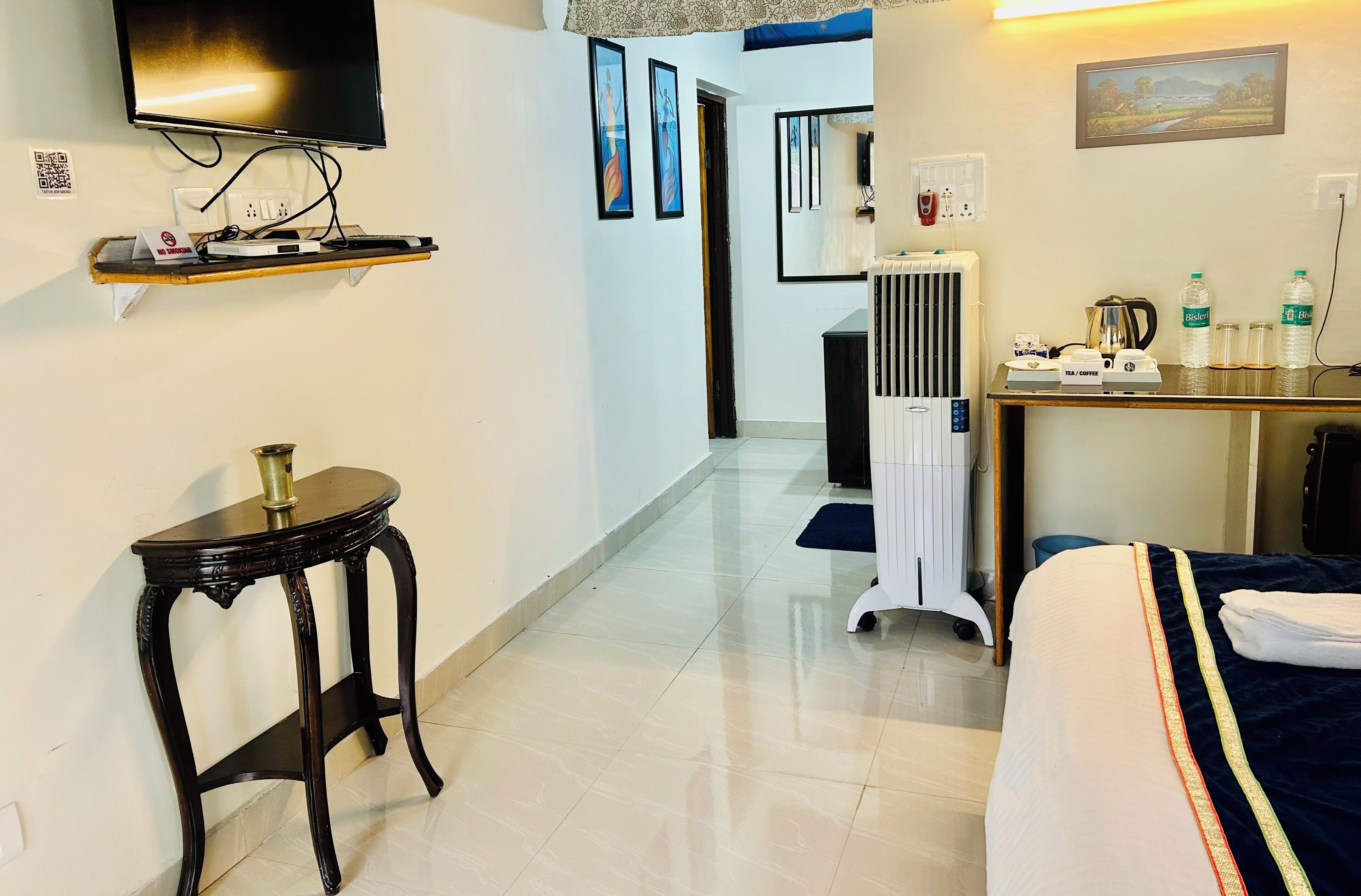 Une chambre d’hôtel avec un lit, une petite table, un téléviseur fixé au mur et un radiateur.