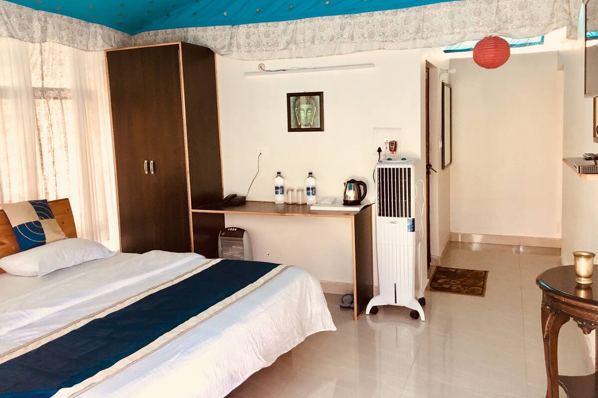 Une chambre d’hôtel avec un lit, un bureau, une armoire, un radiateur et une lanterne rouge.