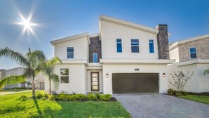 A modern two-story house with a garage, a stone chimney, and a well-maintained lawn.