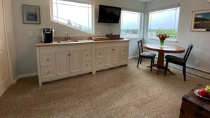 A kitchen with a large island, two windows, a flat-screen TV, and a dining table with chairs. - Gracie's Homer House; Home With A View (Homer)