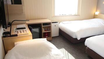 A hotel room with two beds, a desk with a computer, a coffee machine, and a window.