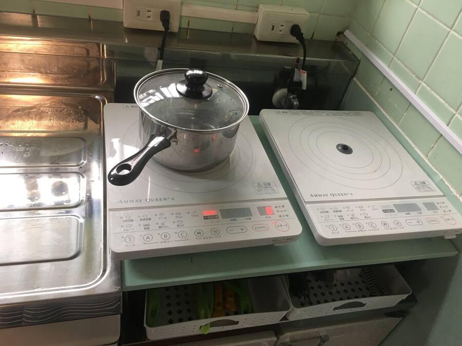 A kitchen with two induction cooktops, a pot on one, and a green countertop.