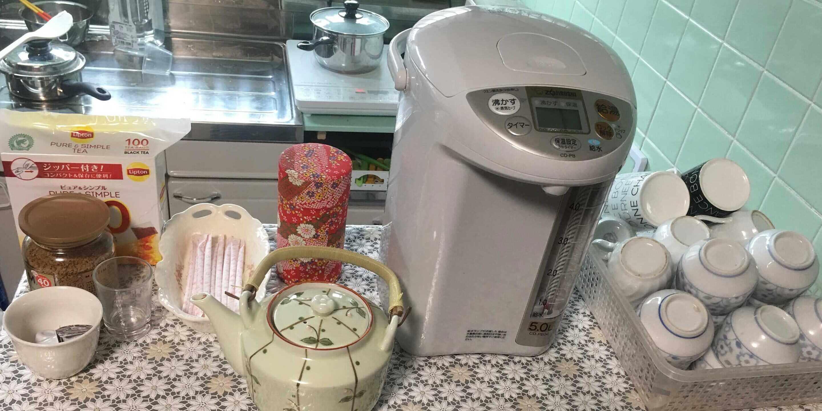 Una cocina con hervidor, cafetera, tarro de té y tetera.