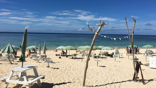 Una playa con tumbonas, sombrillas y un cartel.