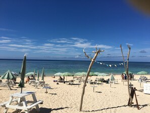 Une plage avec des transats, des parasols et un panneau d’information.