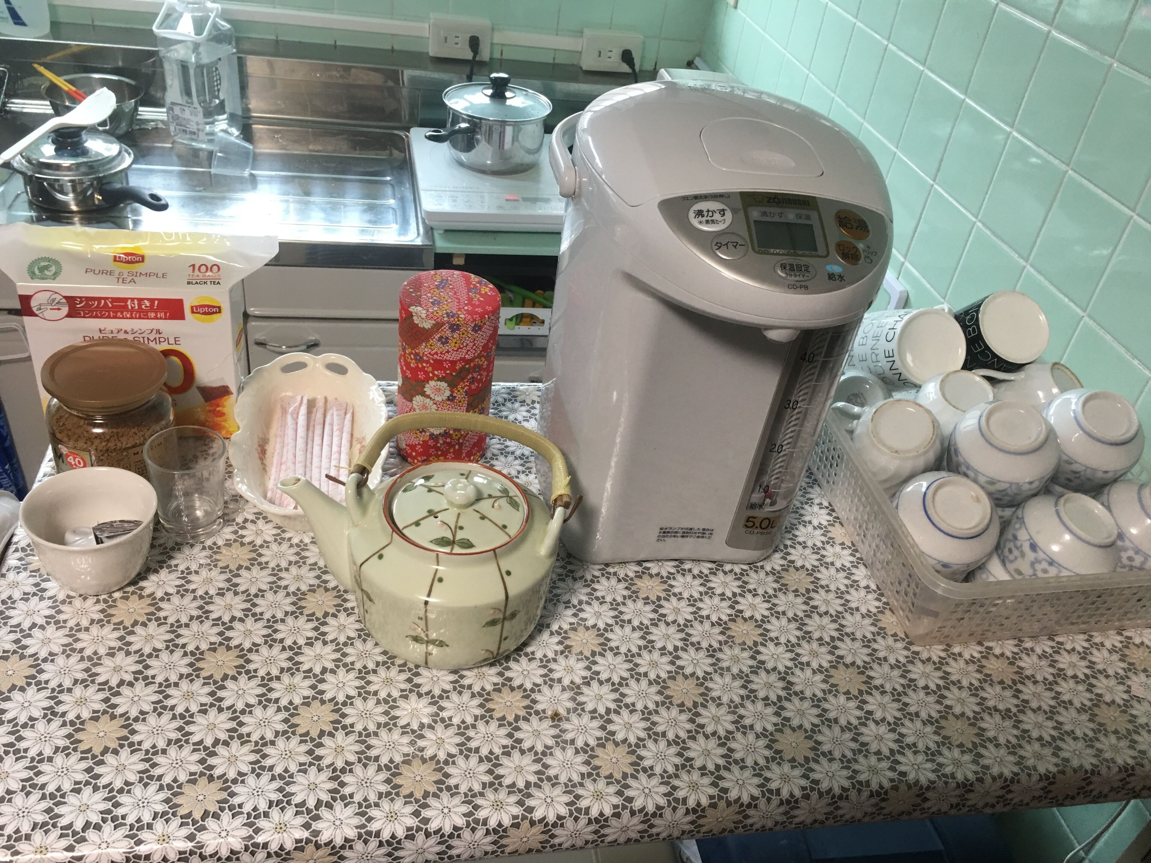 Keittiön työtasolla on kahvinkeitin, teekannu, teepusseja, purkki teetä, kuppi ja pakkaus Lipton-teetä.