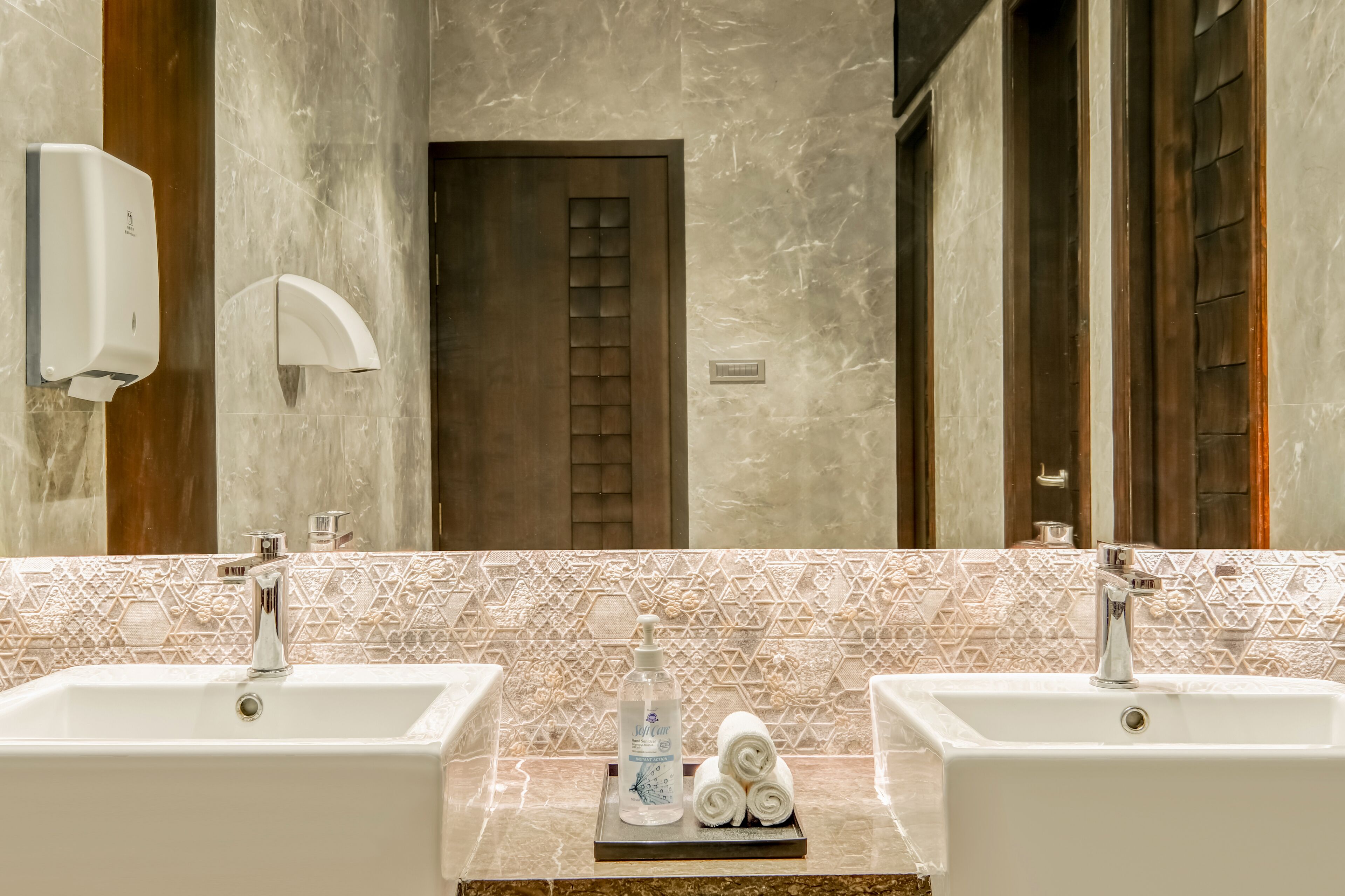 Une salle de bain avec deux lavabos, un distributeur de savon liquide et un porte-serviettes.
