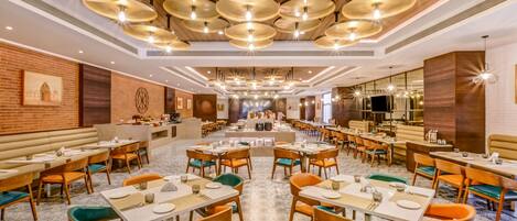 A spacious restaurant with multiple dining tables and chairs, a central bar area, and a patterned floor.