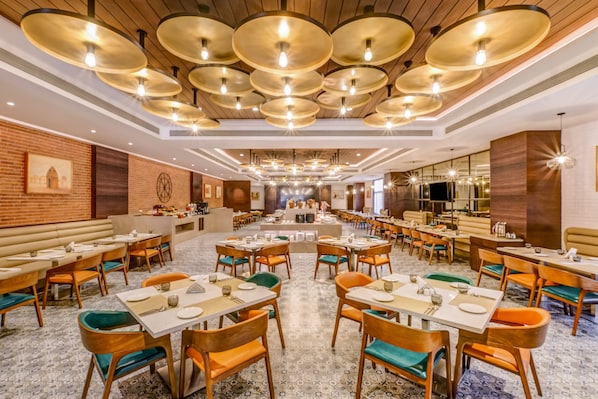 Un restaurante espacioso con numerosas mesas y sillas, una zona de bar central y un suelo con diseño.