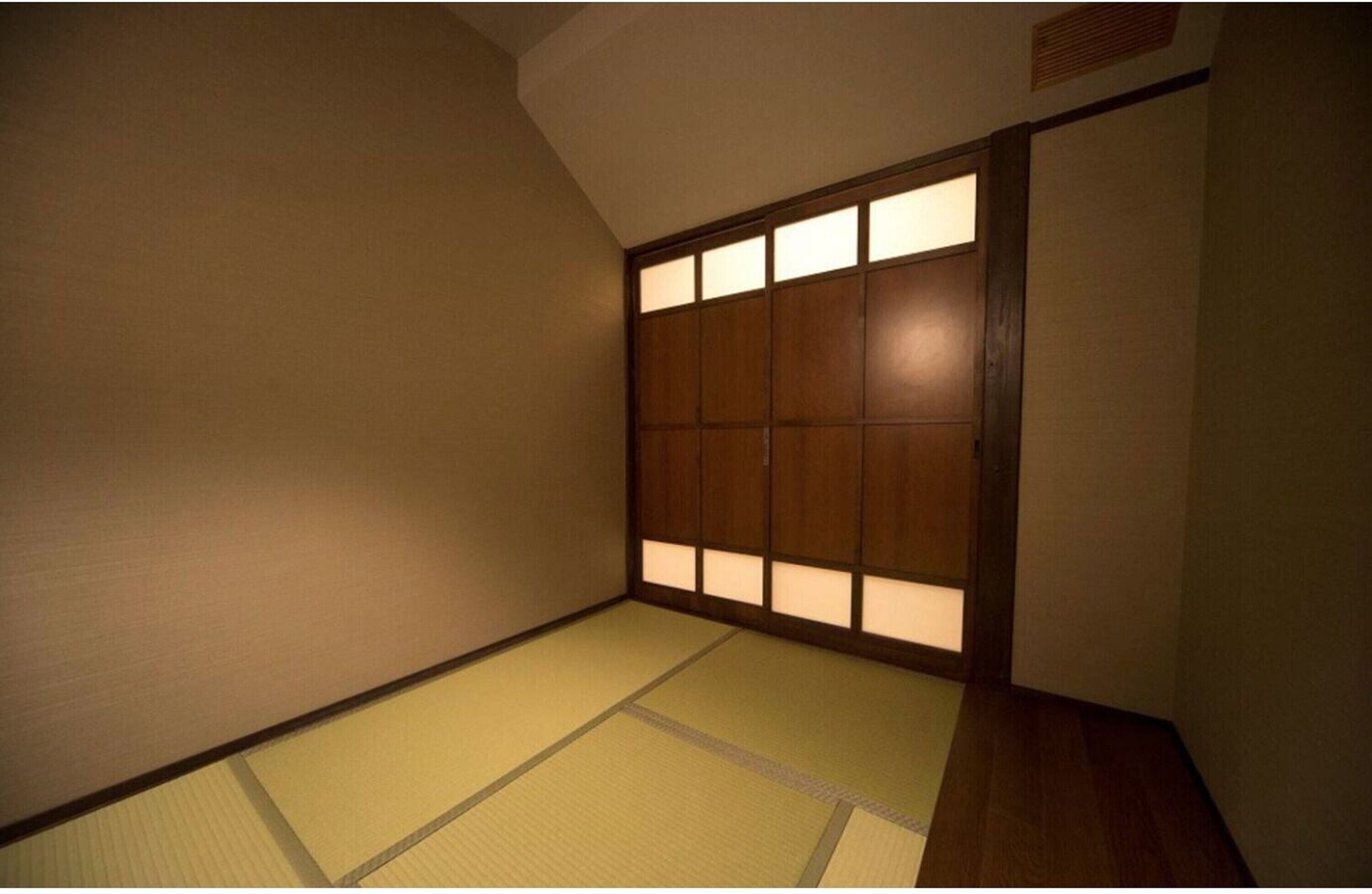 Una habitación japonesa tradicional con suelo de tatami y un fusuma con paneles iluminados.