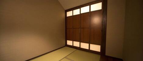 A traditional Japanese room with tatami flooring and a sliding door with illuminated panels.