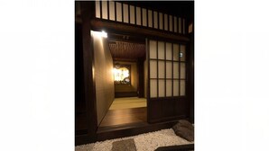 A traditional Japanese interior with tatami flooring, a shoji screen door, and a low wooden threshold. - Hostel Ko-fu (Osaka)