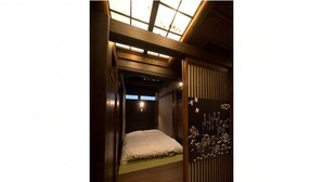 A traditional Japanese-style room with a tatami mat floor, a low wooden bed, and a shoji screen door. - Hostel Ko-fu (Osaka)