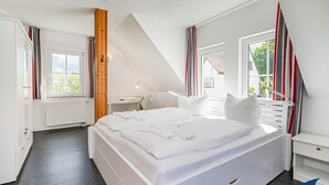 Et soveværelse med en stor seng, et skrivebord og et vindue.