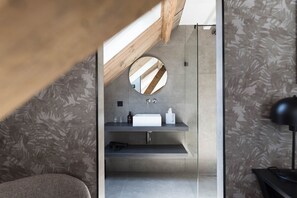 Une salle de bain moderne avec un miroir rond, un lavabo blanc et un porte-serviettes.