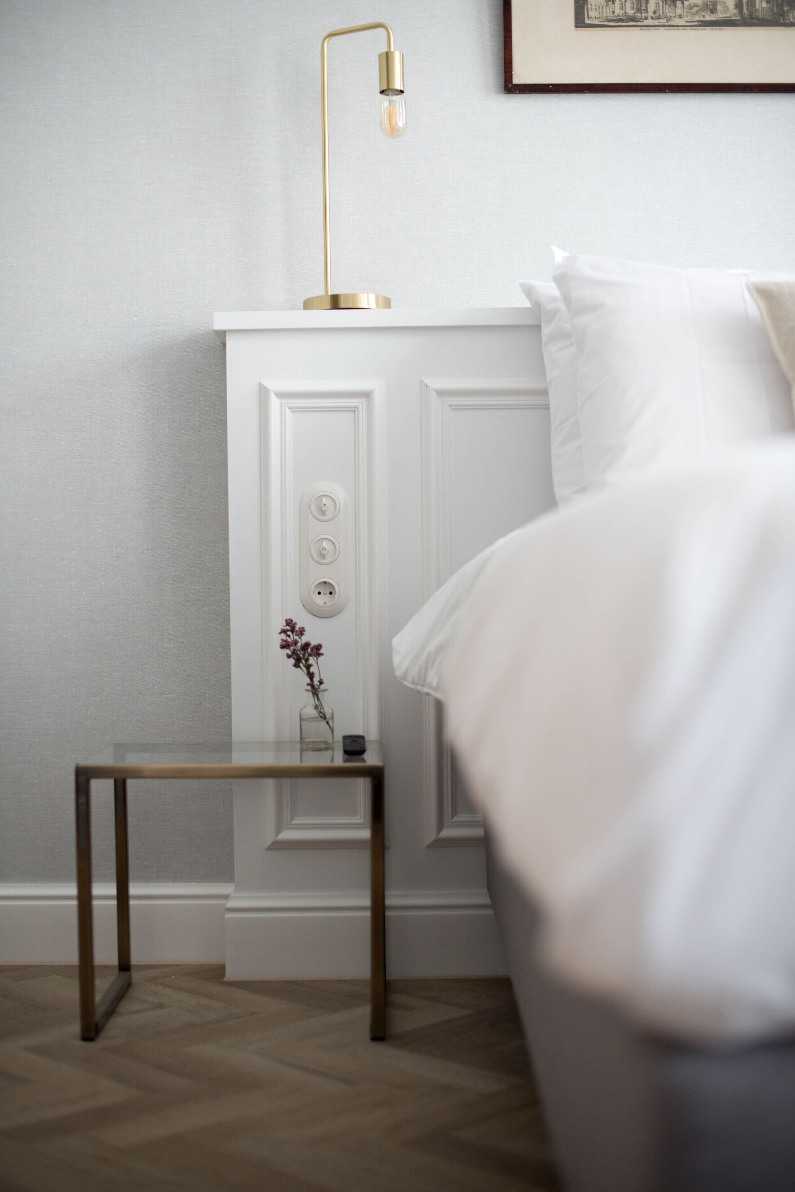 A neatly arranged bedroom with a bed, bedside table, and a lamp.