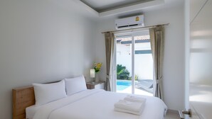 Een hotelkamer met een bed, nachtkastje, lamp, raam met gordijnen en een airconditioning.