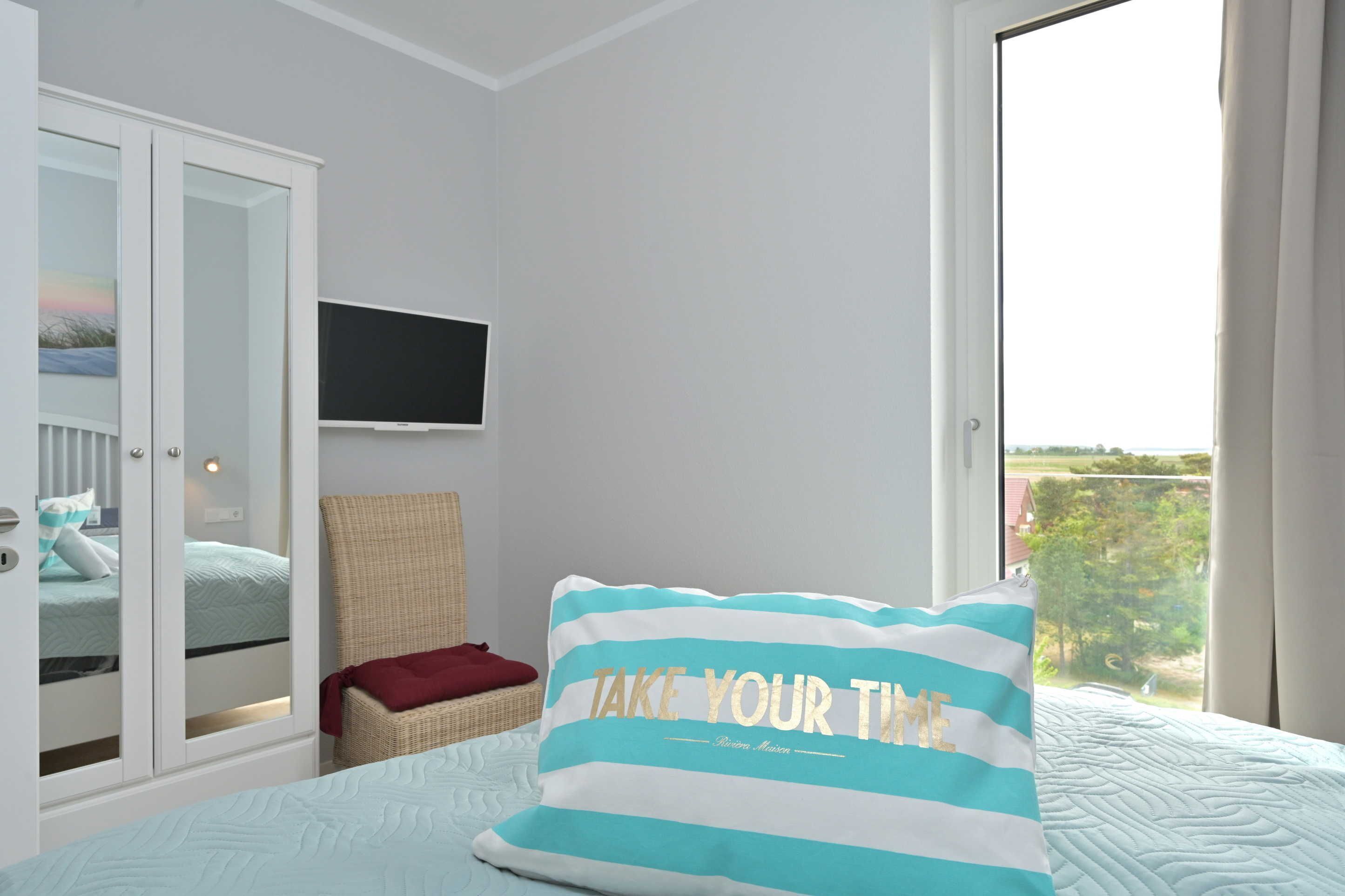 A bedroom with a bed, a television, a wardrobe, and a window with a view.