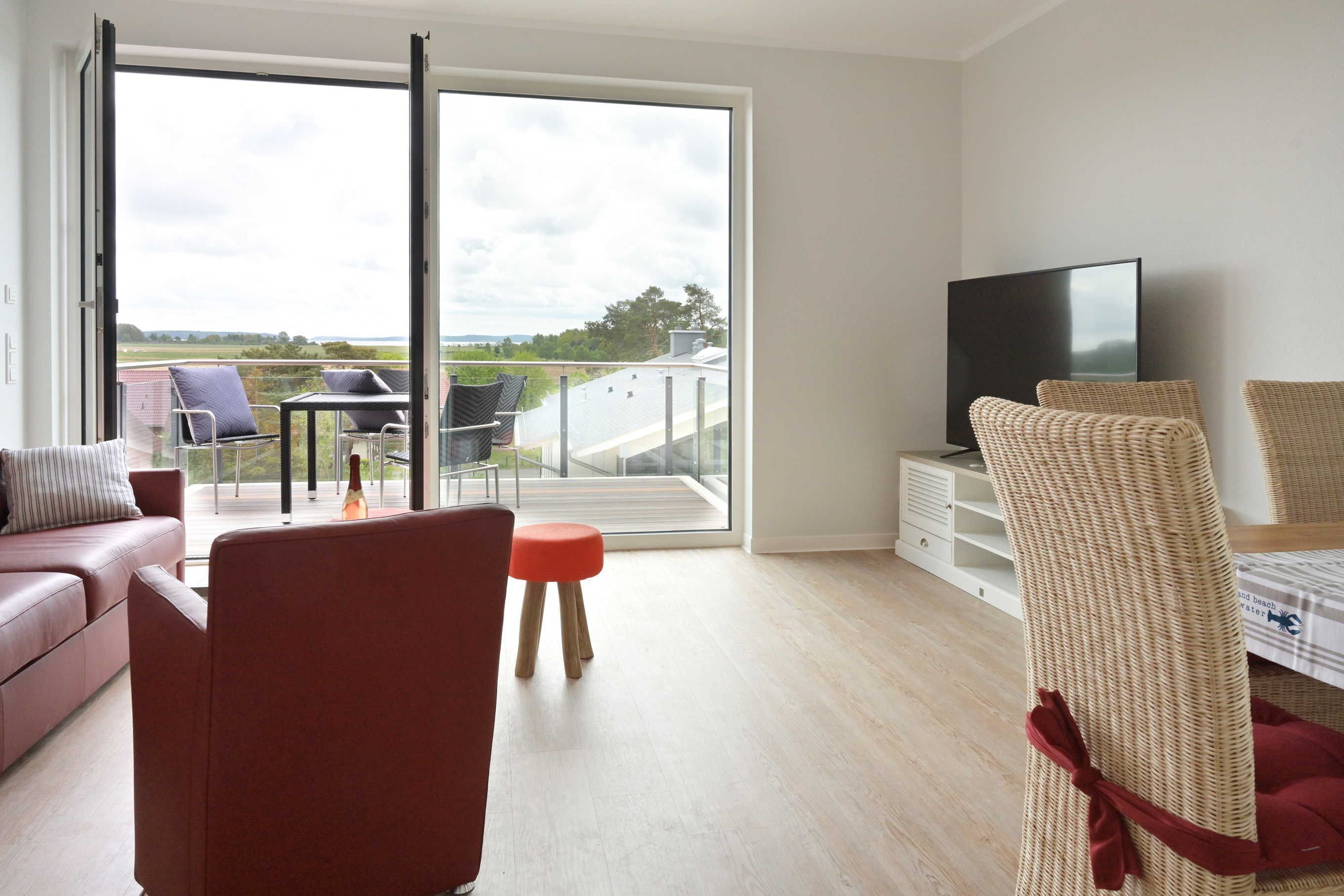 Een moderne woonkamer met een bank, stoelen, een televisie en een balkon met uitzicht.